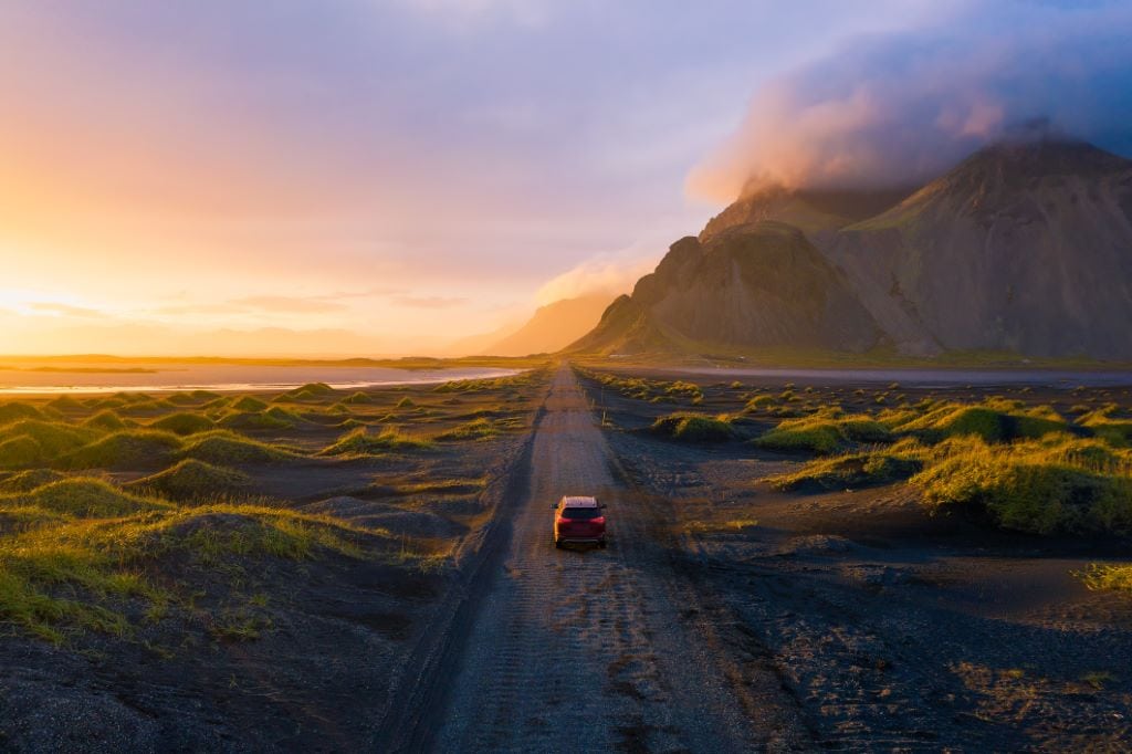Car drivin g on a gravel road towards the sunset in East Iceland