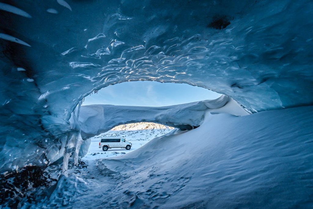 A luxury private vacation experience inside an Icelandic ice cave, with sunlight streaming through the translucent blue ice.
