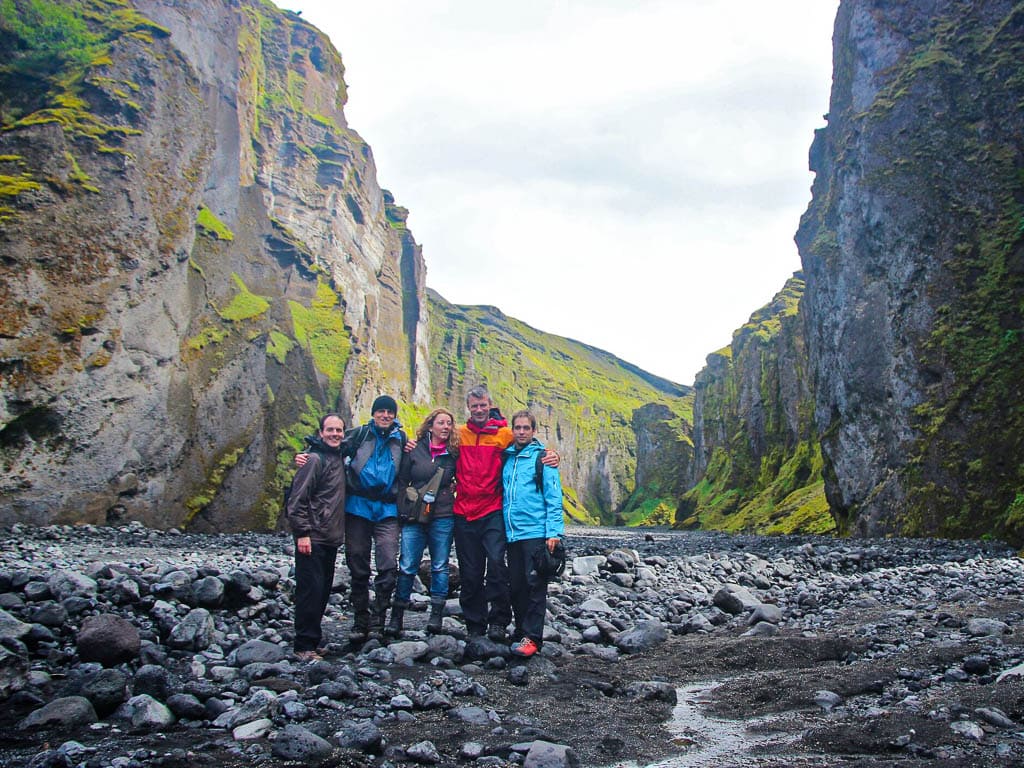 Group of hikers celebrating with raised hands in Thórsmörk's rocky terrain.
