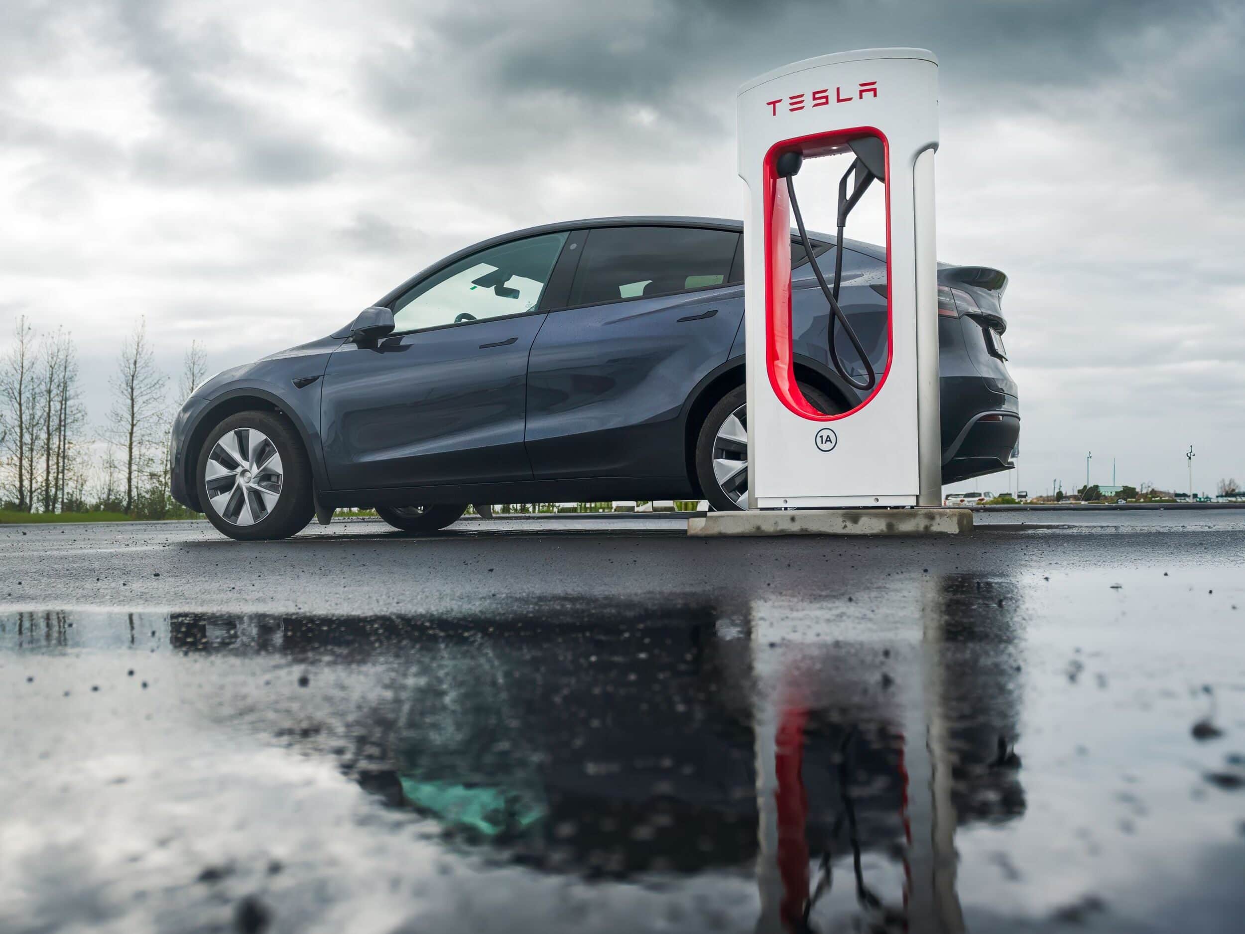 esla Charging Station in Iceland: A Tesla parked at a charging station on a wet reflective surface, promoting carbon-neutral driving in Iceland's natural surroundings.