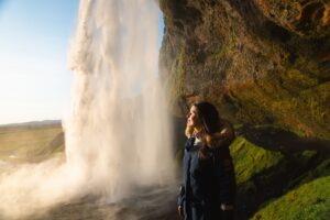 woman standing by a waterfall in the evening sun
