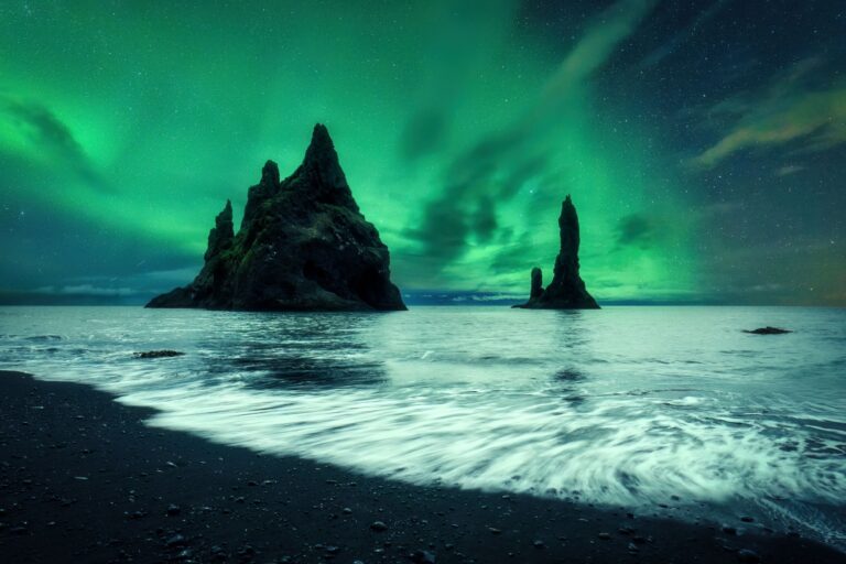 Green northern lights dancing over the cliffs of Reynisfjara