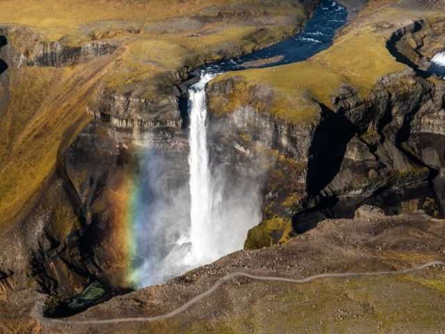Scenic waterfall with a rainbow in the Iceland Highlands during a Landmannalaugar tour.
