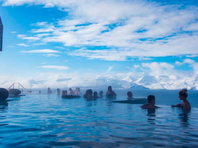 People enjoying the view over the North Atlantic ocean from the warm water infinity pool at GeoSea Baths in North of Iceland