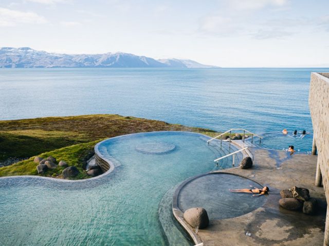 People enjoying the view over the North Atlantic ocean from the warm water infinity pool at GeoSea Baths in North of Iceland