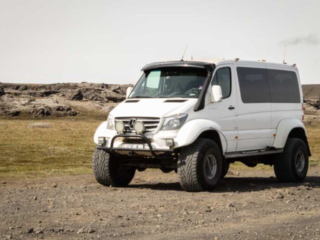 White superjeep parked against a rocky hill in the Iceland Highlands on a Landmannalaugar tour.