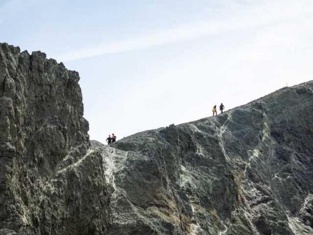 Hikers standing on a rocky peak in Landmannalaugar, Iceland Highlands.