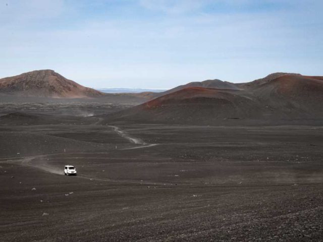 Superjeep driving across a volcanic landscape in the Iceland Highlands during a Landmannalaugar tour.