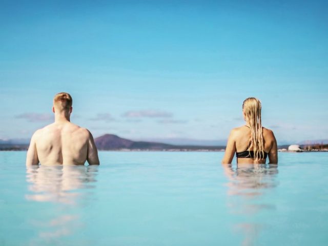 Man and woman standing in milky-blue geothermal water