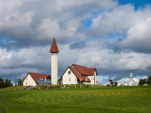 White church with red roof under a cloudy sky in Reykholt, part of the Silver Circle in Iceland.