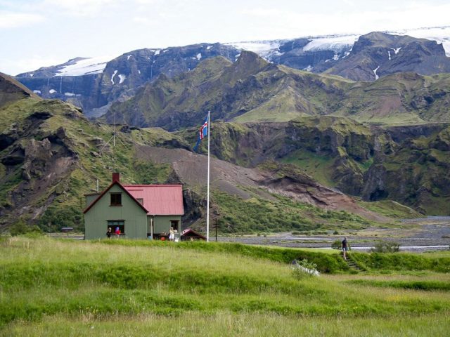 Lonely house amidst green fields with mountains in the background in Thórsmörk.