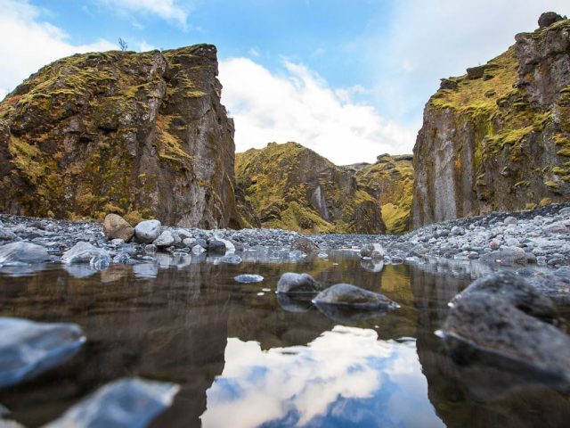 Reflection of towering cliffs in a still water pool in Thórsmörk.