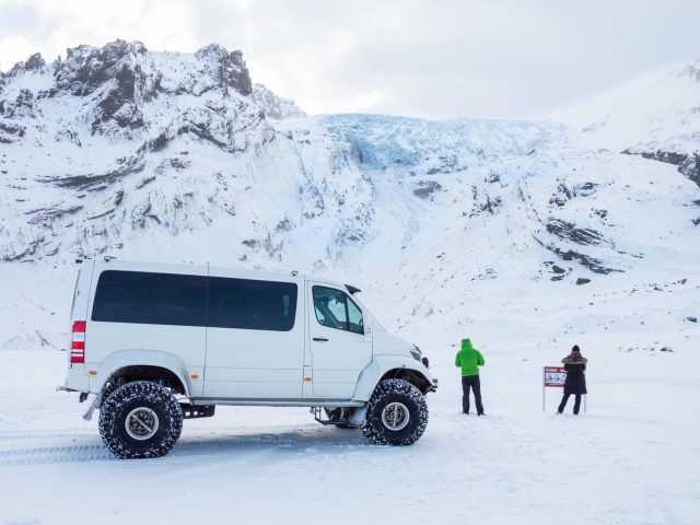 Private luxury vacation scene with a super jeep parked on a snowy trail in Iceland, surrounded by pristine winter beauty.