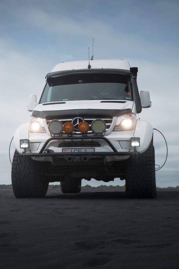 White monster truck parked on a stretch of black sand.